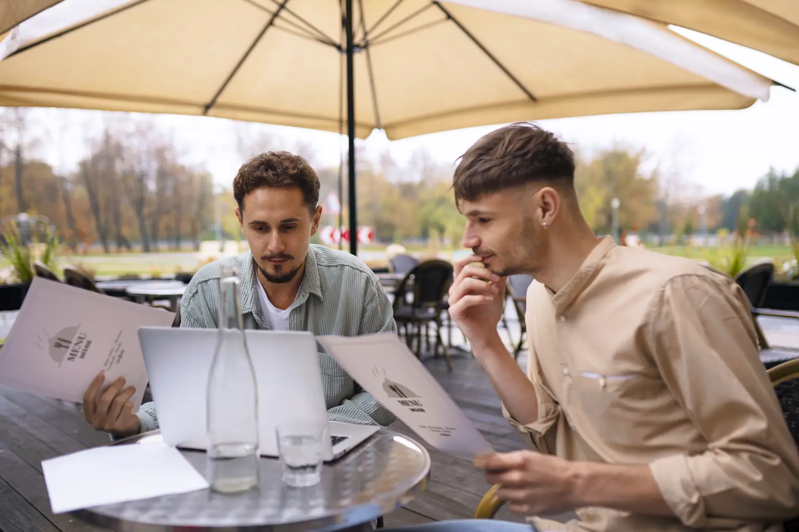 Two customers reviewing restaurant menus at outdoor patio dining area in Bay City Michigan